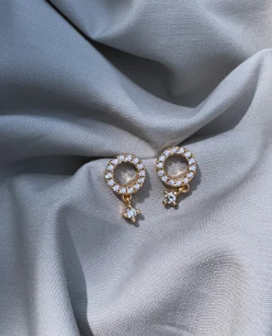 Drop earrings with clear-stone circles on grey fabric