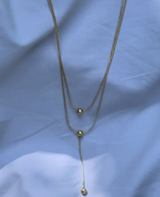 Layered fine chain necklace with ball drops on blue fabric