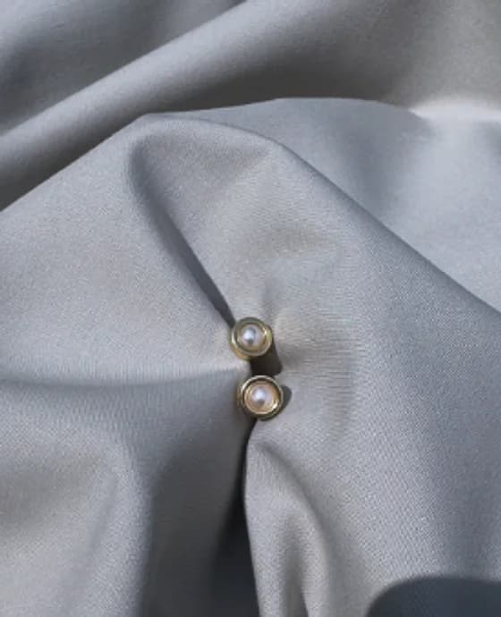 Pearl-look stud earrings on grey fabric