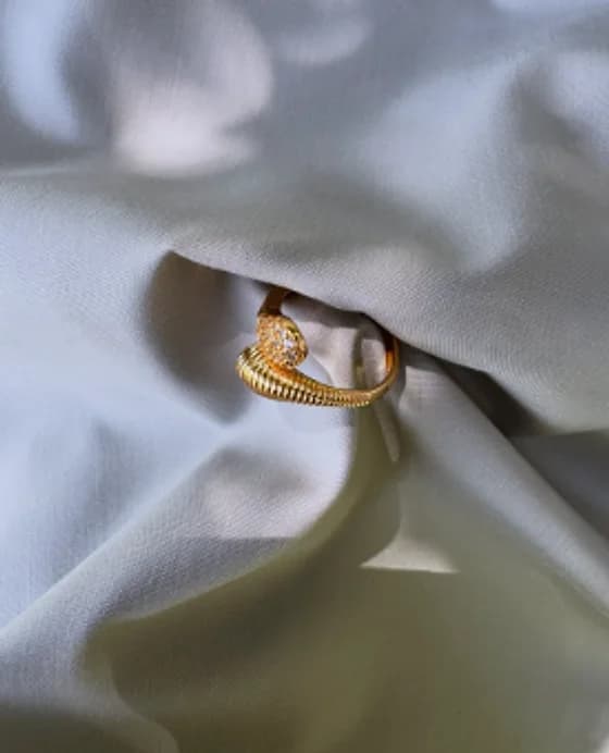 Ribbed gold-tone open ring on grey fabric