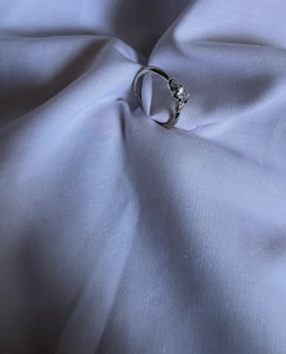 Gold-tone ring with a clear stone on lavender fabric
